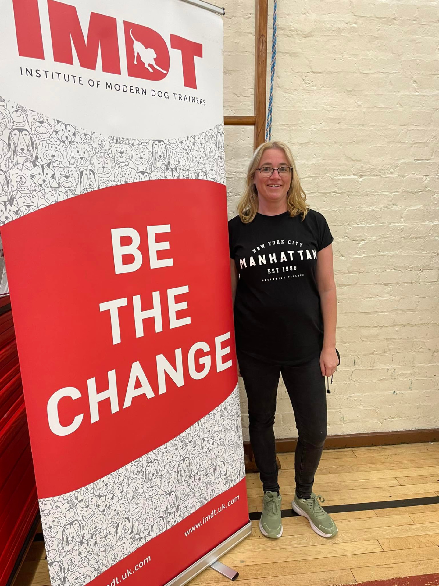 Dog trainer standing next to an IMDT 'Be the change' banner